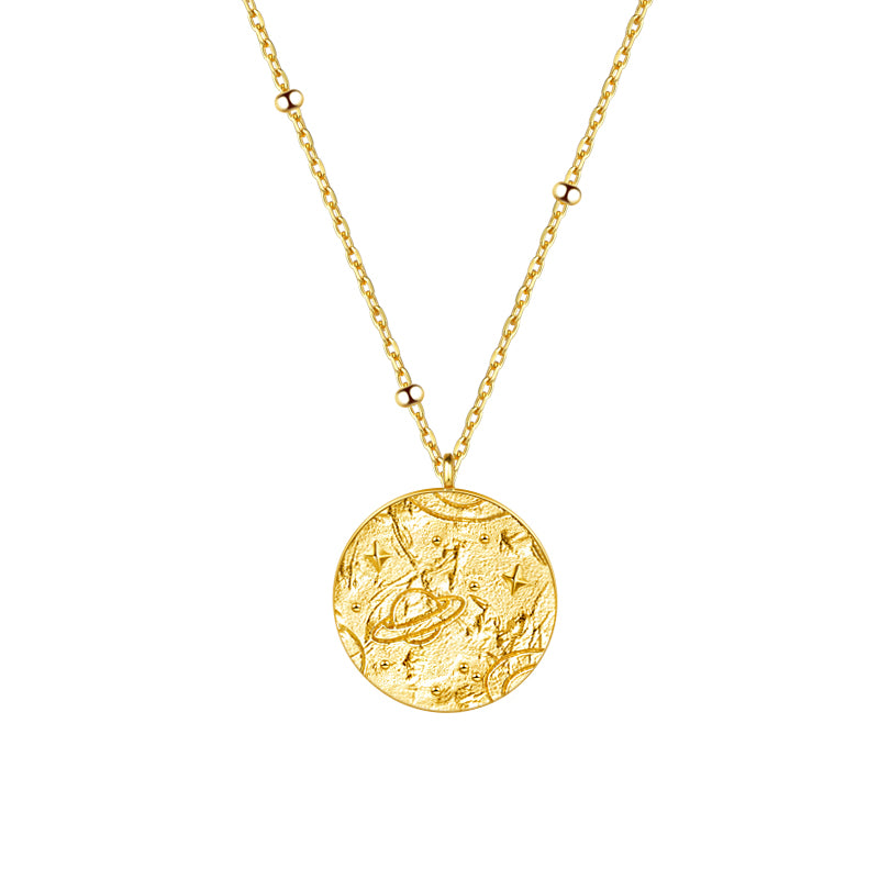 Gold necklace with a round pendant featuring an intricate celestial design of planets and stars, elegantly hanging from a delicate chain.